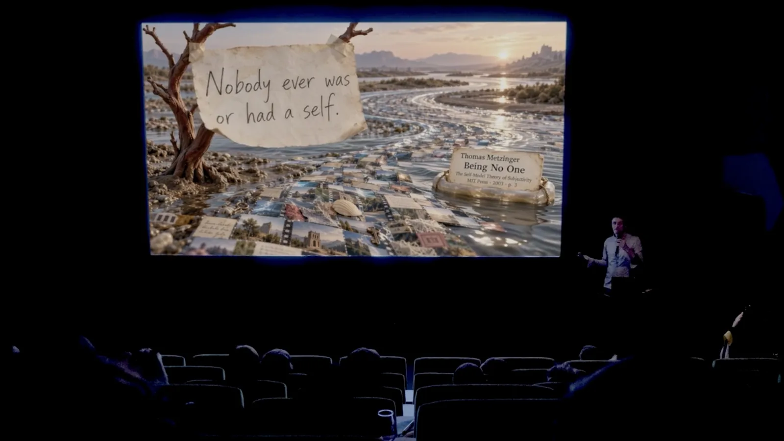 The cinema during the performance. On screen, a handwritten note pinned to a tree by a river of photographs: Nobody ever was or had a self. Thomas Metzinger, Being No One, MIT Press 2003, p. 3. Jhave speaks at the right of the screen.
